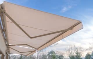 A beige retractable awning shades a patio—Are Retractable Awnings Good in the Rain? Best Awning Company explains their weather-ready benefits.