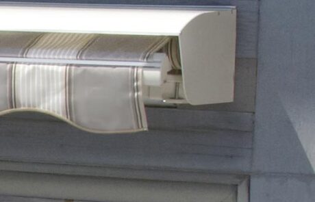 Retractable window awning with striped fabric cover.