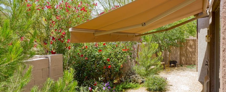 Can a Retractable Awning Work on a Curved or Angled Wall Backyard with awning and lush greenery