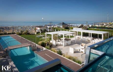 Beachfront pool area with seating and umbrellas.