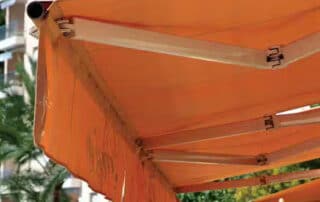Orange retractable awning extending over an outdoor patio area, illustrating key factors to consider when selecting an awning. Common Mistakes When Choosing a Retractable Awning image.