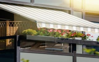A retractable awning shades a sunny balcony—How to Get Your Awning Ready for the Summer Season? Best Awning Company shares seasonal prep tips.