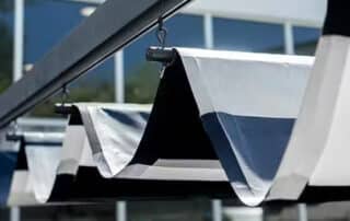 Modern outdoor canopy shades installed on a commercial building, demonstrating how awnings help reduce energy costs. Use Commercial Awnings to Reduce Bills