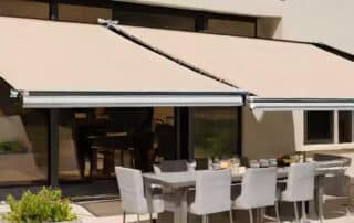 Modern patio featuring retractable awnings and an outdoor dining set, emphasizing essential care and upkeep. Retractable Awning Maintenance Tips image.