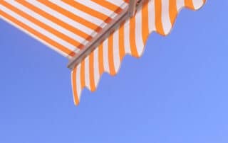 Orange and white striped awning against blue sky