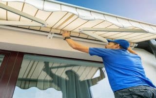 A worker installs an awning above a terrace window—What to Look for in an Awning Installation Company? Best Awning Company offers a helpful checklist.