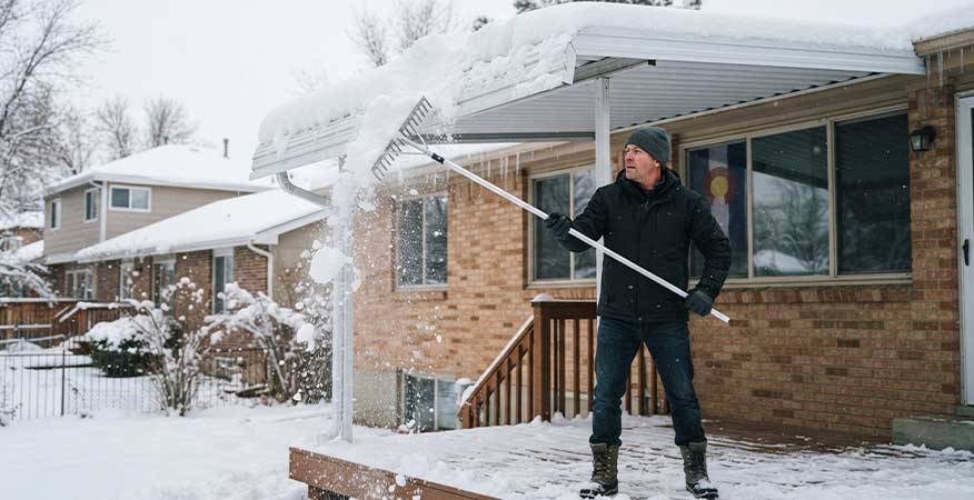 clearing snow from aluminum awning with roof rake